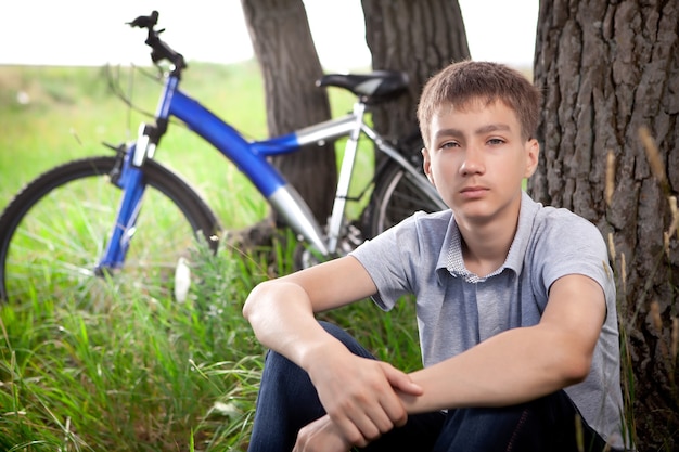 芝生の上の公園で自転車を持っている少年