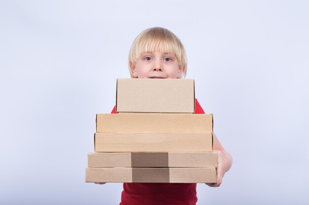 Boy with blond hair holding many cardboard box