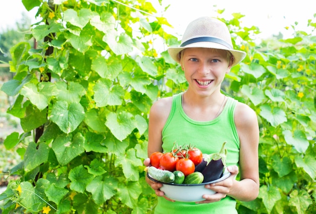 A boy with a bowl of vegetables in the garden