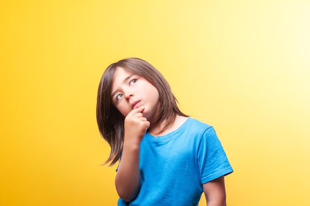 茶色いの少年がひげに手をつけて青いシャツを着て思慮深いポーズをとっています
