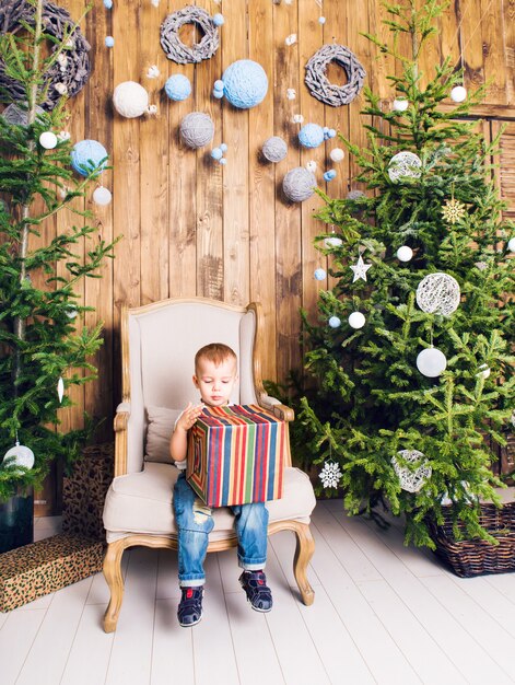 クリスマスツリーの近くのクリスマスプレゼントを持つ少年