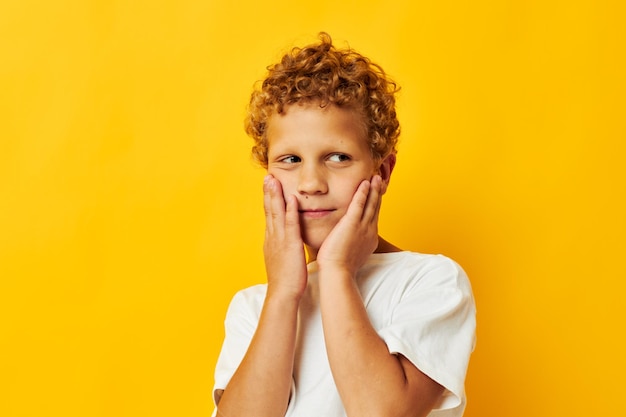 Boy with curly hair in a white tshirt on a yellow background