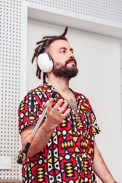 Photo boy with dreadlocks and ear protections holds a percussion mace