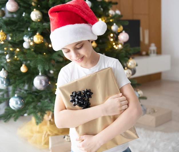 Boy with gifts plays near the Christmas tree. Living room interior with Christmas tree and decorations. New Year. Gift giving.