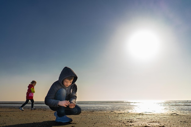 Boy with a girl walks around the lake on a summer day and collected seashells on a beach