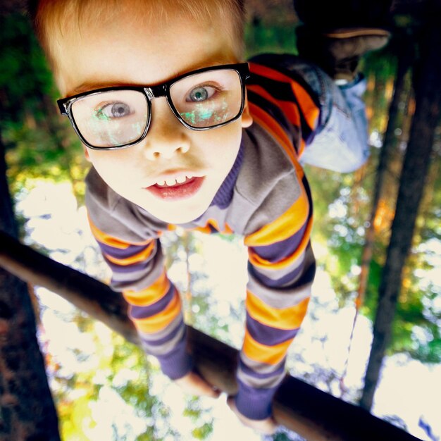 Foto ragazzo con gli occhiali che gioca nel parco giochi nel parco