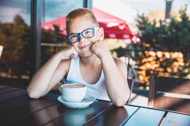 Мальчик в очках в ресторане, пить кофе