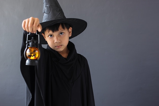 A boy with halloween costume and holding a lantern