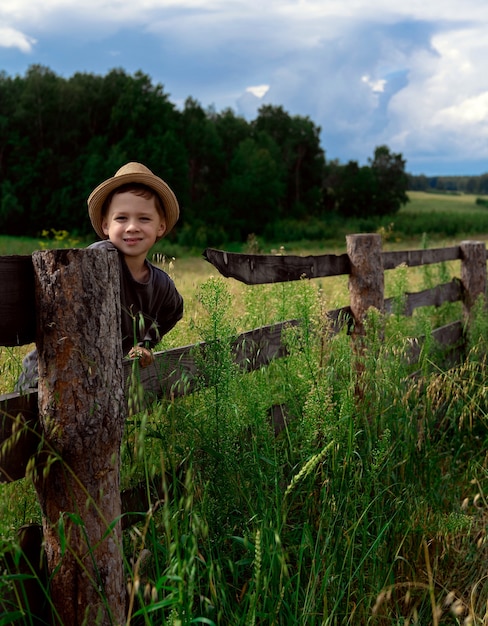 Boy with hat sitting on the fence