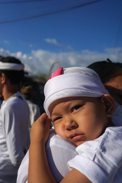 Boy with head cover dreamy on his mothers shoulder