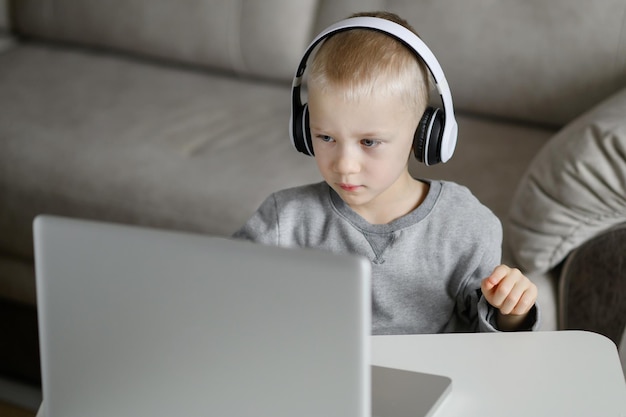 The boy with headphones carefully watch the video tutorial on the computer