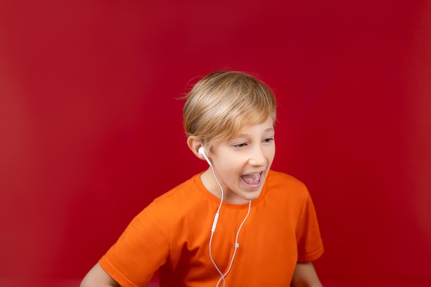 Мальчик с наушниками в ушах стоит боком и поет