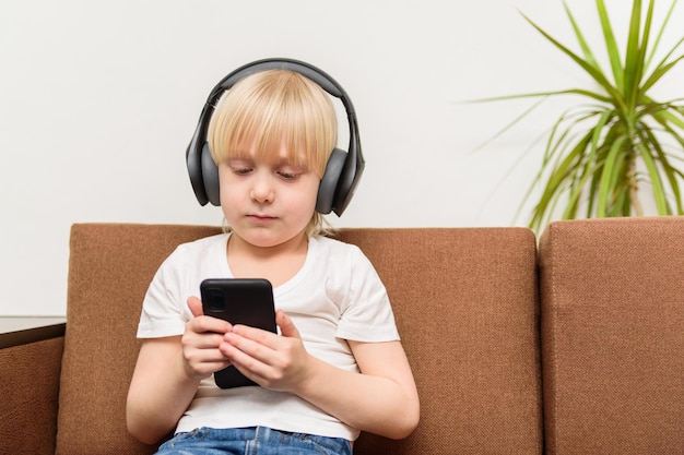 Мальчик в наушниках держит телефон Зависимость от социальных сетей