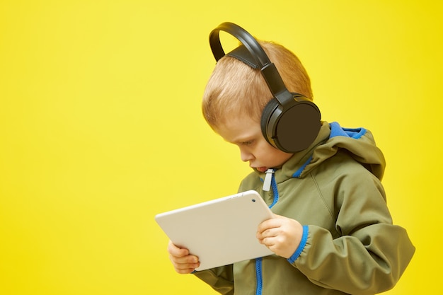 A boy with headphones is studying a tablet computer