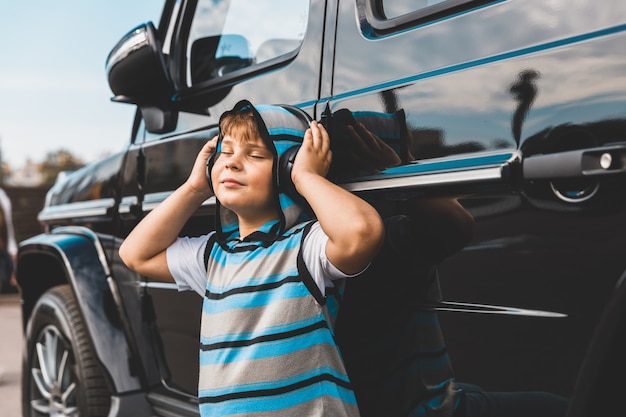 Boy with headphones listening to music next to the car