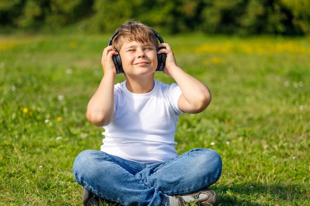 Ragazzo con le cuffie che ascolta la musica mentre era seduto sull'erba