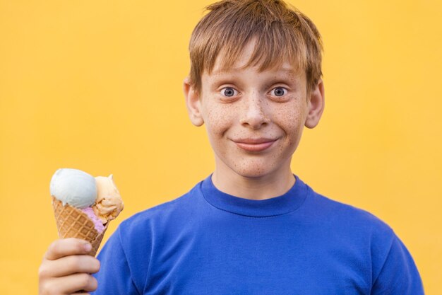 黄色い壁の近くにアイスクリームを持った少年