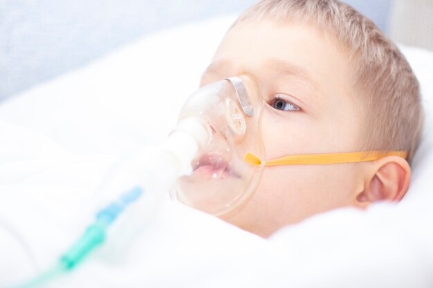 Boy with an inhaler mask in bed