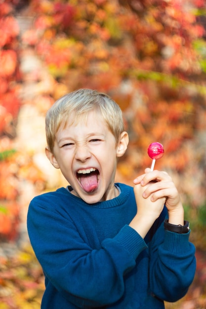 boy with a Lollipop in his hands shows funny faces