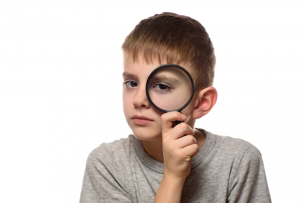 Boy with a magnifying glass in his hands. Little explorer. White 