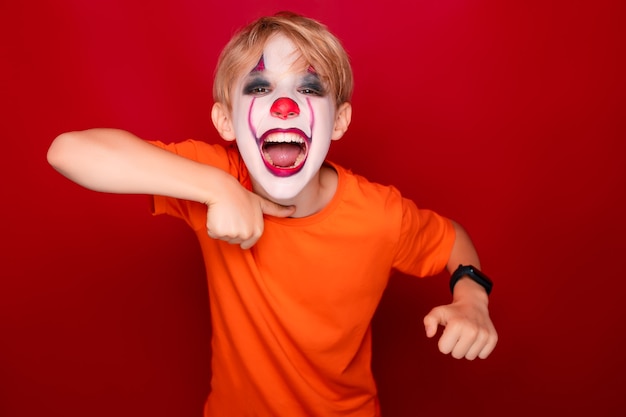 Boy with makeup before halloween screams loudly and shows threatening gestures.