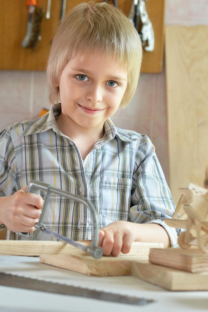 船と手のこぎりのモデルを持つ少年