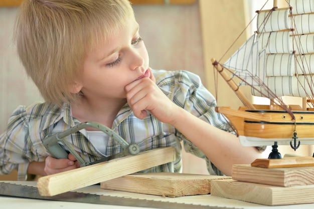 Boy with model of ship and handsaw