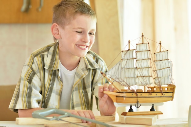 Boy with model of ship and handsaw