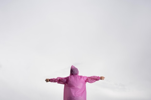 Boy with open arms wearing disposable raincoat