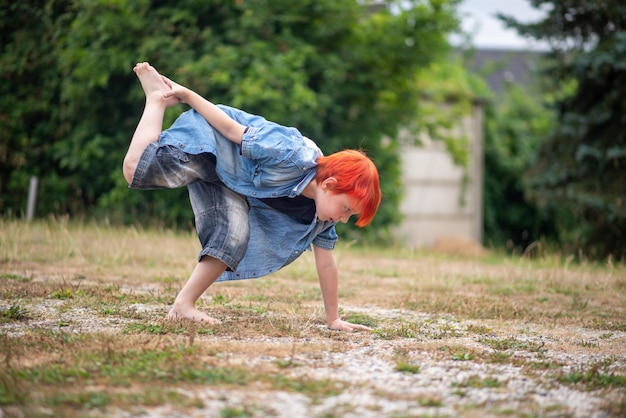 A boy with orange hair is doing a yoga pose.