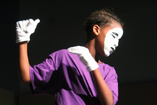 Photo boy with painted face dancing against black background