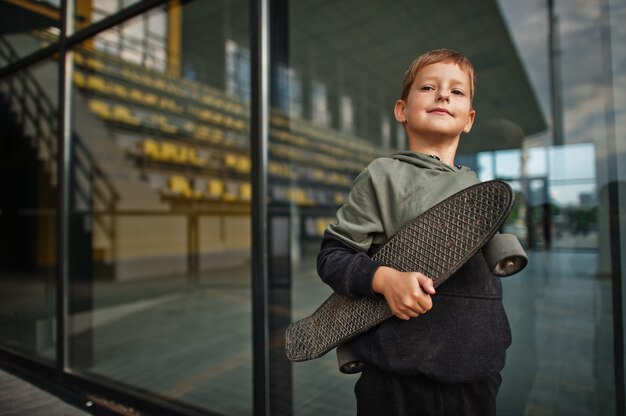 Boy with penny board in hands at stadium.