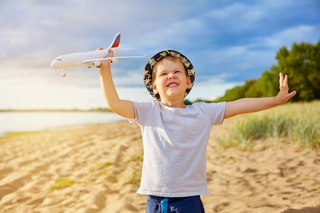 ビーチで彼の手で飛行機を持つ少年