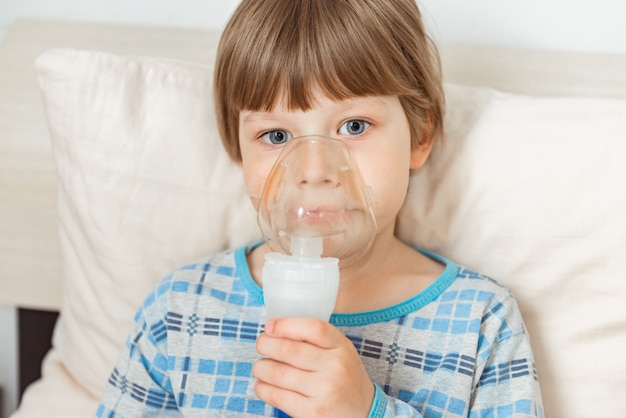 Boy with a respiratory syncytial virus, inhaling medication through an inhalation mask. Flu, coronavirus concept