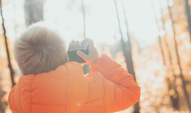 Boy with retro camera taking pictures outdoor in autumn nature leisure and photographers concept