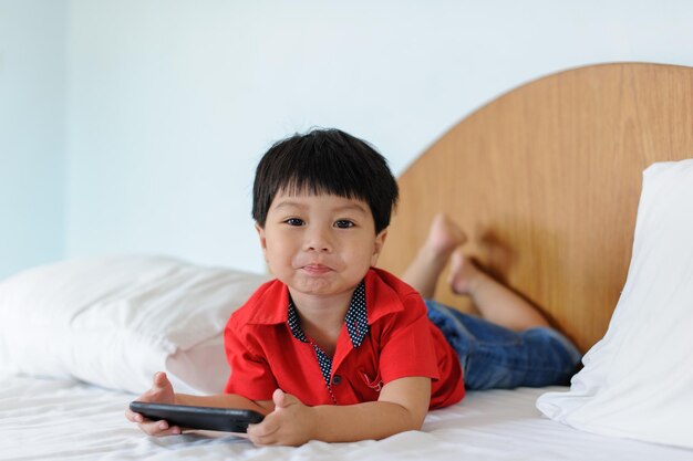 Photo boy with smartphone texting message or playing game at home