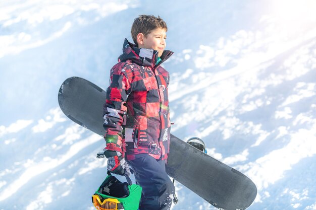 Photo boy with snowboard in the mountain winter resort