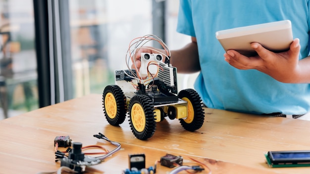 Boy with tablet pc computer programming electric toys and building robots. 