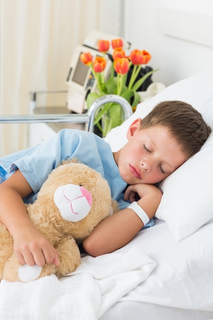 Мальчик с плюшевым медведем спит в больнице