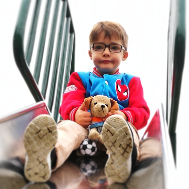 Boy with toy sitting on slide