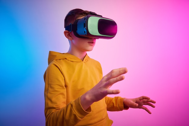 Photo boy with virtual reality glasses on the colorful background. future technology, vr concept