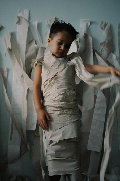 Photo boy wrapped in toilet paper standing at home