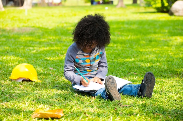 Boy writing in book on grass