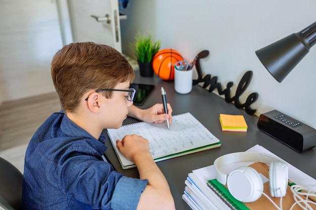 Foto ragazzo che scrive in un libro sul tavolo