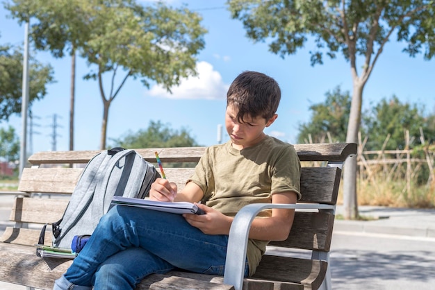 写真 ベンチに座って本を書いている少年