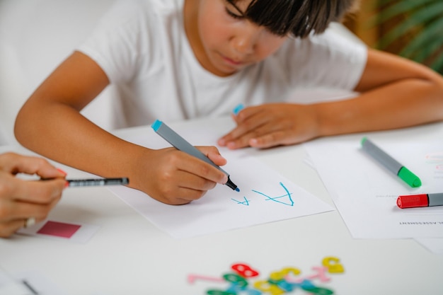 Boy writing letters on preschool screening test