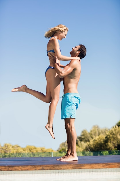 Boyfriend carrying his girlfriend by the pool