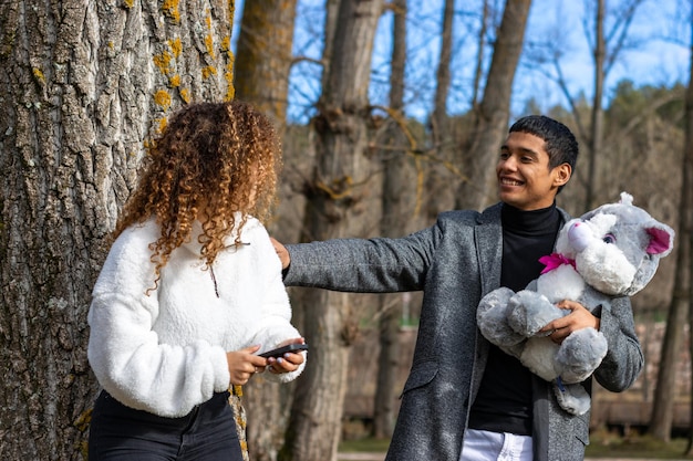 Boyfriend giving a teddy to girlfriend outdoors Young latin man giving teddy bear to girlfriend