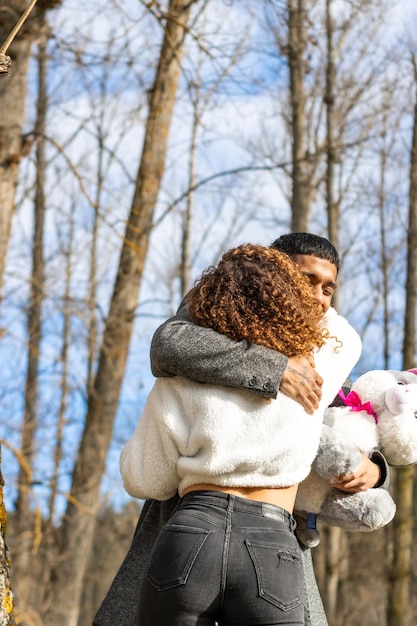 Boyfriend hugging girlfriend while holding a teddy bear Man in love hugging girlfriend while holding teddy bear outdoors