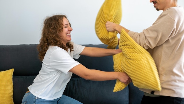 Парни весело играют вместе на диване дома, сражаясь с подушкой